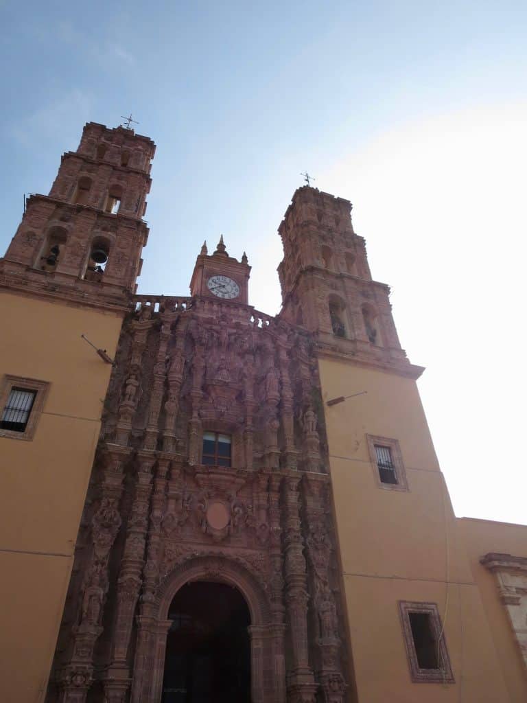 picture of a yellow and stone church, with the blue sky.