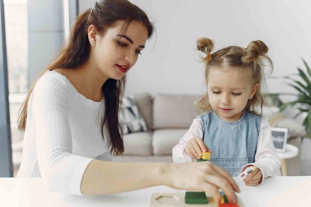 Au pair young girl playing with a toddler girl