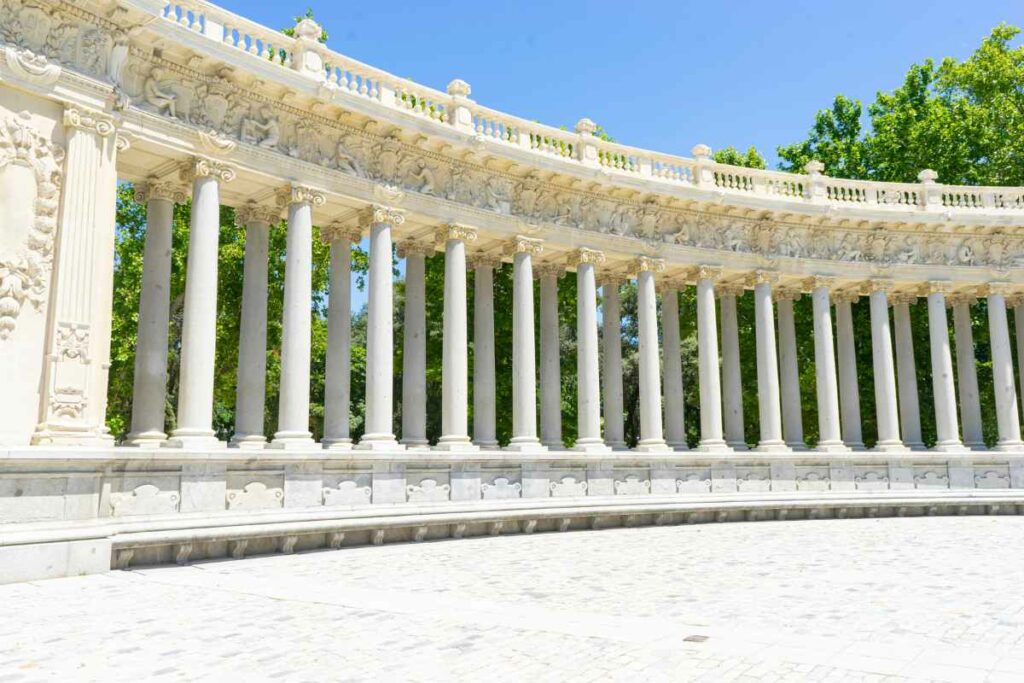 A curved row of classical columns in a bright outdoor setting, part of an elaborate architectural structure with intricate carvings.