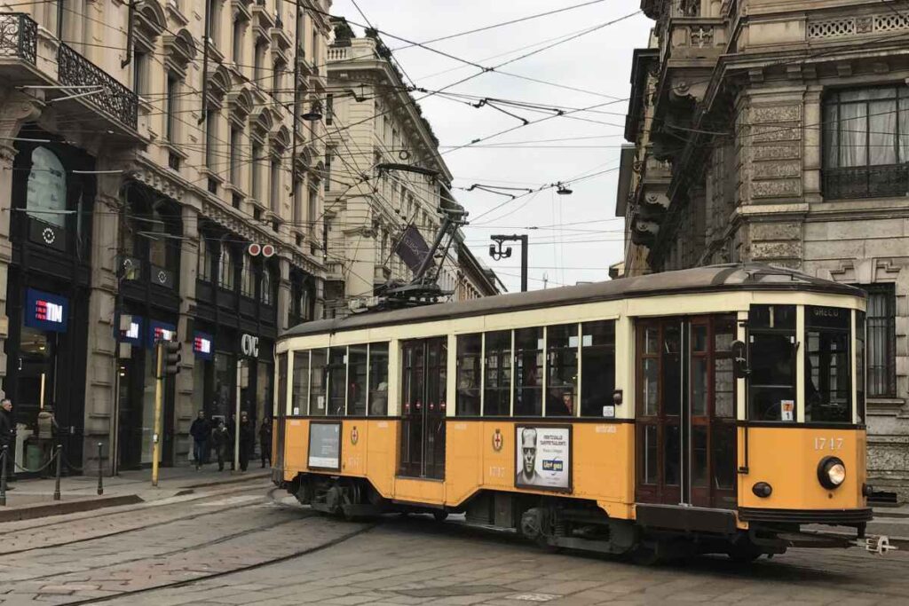 A vintage yellow tram glides through the streets of Porto, surrounded by ornate European architecture. This iconic scene captures the essence of why Porto, Portugal, is worth visiting.