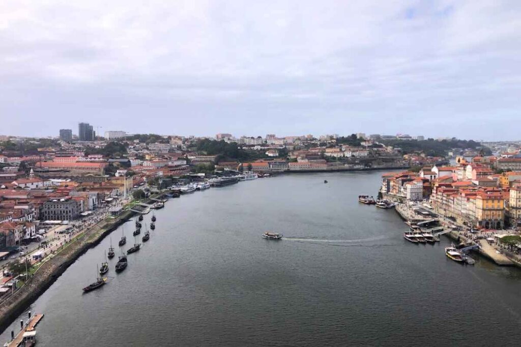 A serene view of the Douro River with traditional boats and colorful riverside buildings in Porto, Portugal. Is Porto Portugal worth visiting for these breathtaking riverside vistas? Definitely.