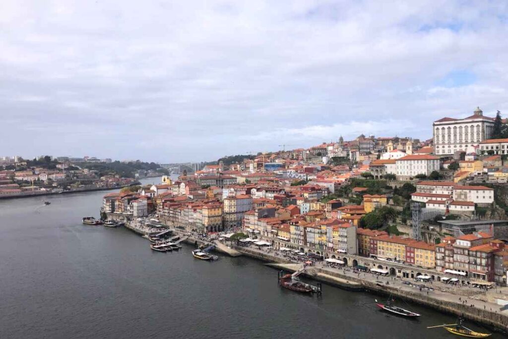 A street view of Porto's traditional buildings with colorful rooftops next to a striking blue-tiled chapel. Is Porto Portugal worth visiting for its vibrant and picturesque streetscapes? This image says yes.