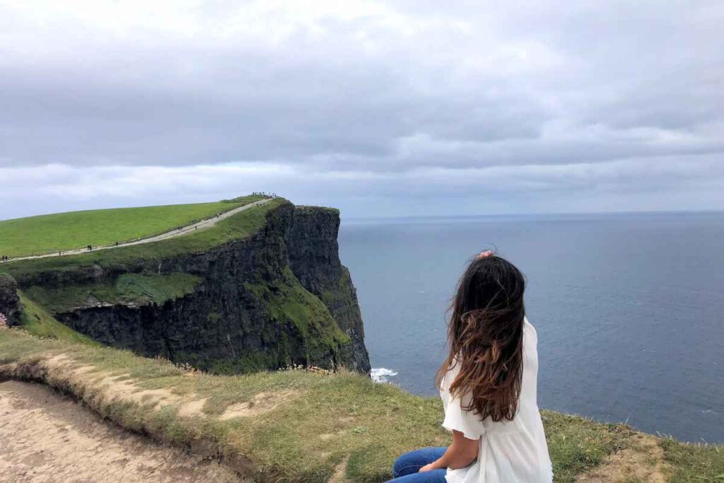 A solo traveler admiring the breathtaking Cliffs of Moher in Ireland, one of the best scenic spots for solo female travelers. Included in the 13 Best of Solo Female Travel Europe Destinations.