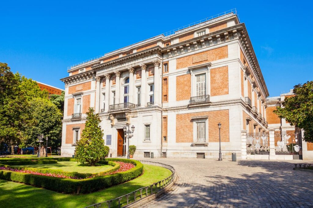 The beautiful red-brick façade of the Prado Museum, one of the most famous art museums in the world. Staying near the Prado is ideal for first-time visitors who love culture and history. Where to stay in Madrid for the first time.