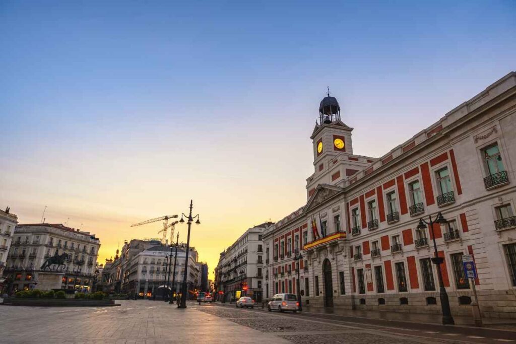 The famous Puerta del Sol at sunset, featuring the clock tower of the Real Casa de Correos. A central area to consider when deciding where to stay in Madrid for the first time.