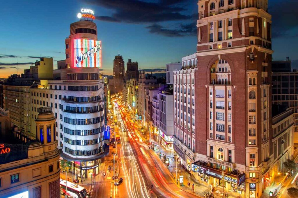 Gran Vía at night, with its iconic Schweppes sign and bright city lights. This area is great for nightlife and a top choice for where to stay in Madrid for the first time.