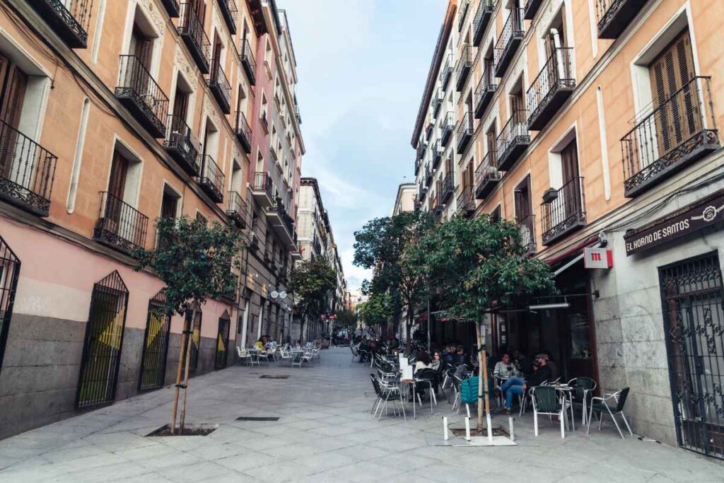 Outdoor café seating along a quiet street in Madrid, surrounded by elegant architecture. Ideal for travelers looking for a relaxed atmosphere while choosing where to stay in Madrid for the first time.