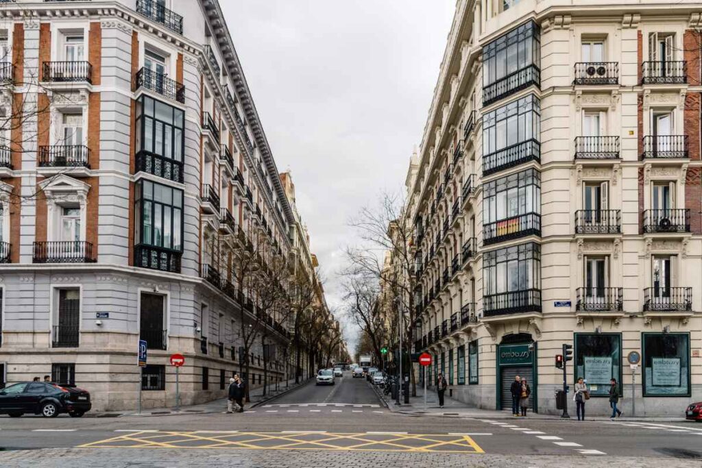 A wide, elegant street in Madrid lined with historic buildings, perfect for a first-time visit. The upscale neighborhood provides easy access to top attractions and dining options. Where to stay in Madrid for the first time.