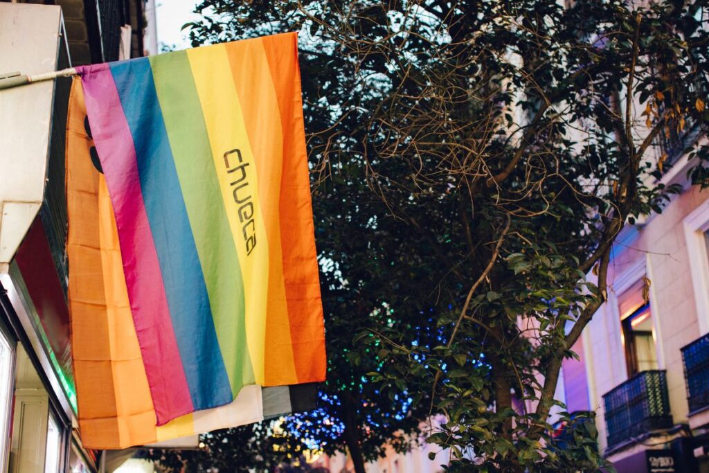 A rainbow flag with “Chueca” written on it, representing Madrid’s LGBTQ+ district. Chueca is a vibrant and welcoming area to consider when deciding where to stay in Madrid for the first time.