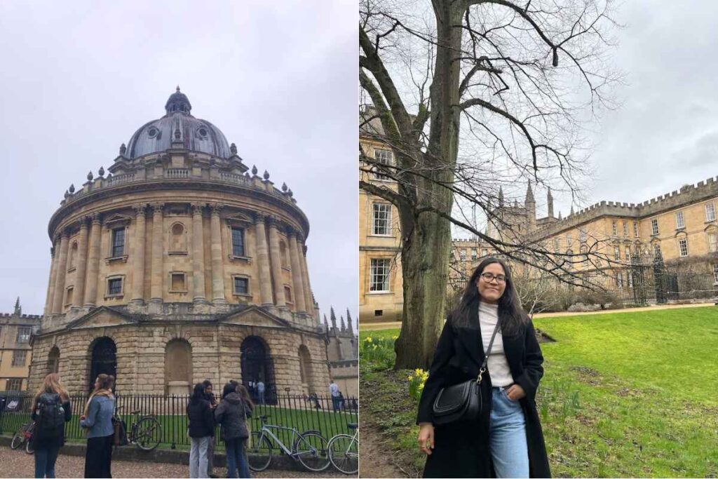 A grand, circular sandstone building with a domed roof, known as the Radcliffe Camera, stands in Oxford, England. Several people with backpacks and warm coats are gathered outside the black wrought-iron fence, while bicycles lean against it. On the right, a solo female traveler with long dark hair, glasses, and a black coat over a white turtleneck stands on a patch of bright green grass, smiling at the camera with historic Oxford architecture and a leafless tree behind her. Oxford is a must-visit for history lovers and is featured in the 13 Best of Solo Female Travel Europe Destinations.